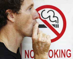 man smoking a no-smoking sign