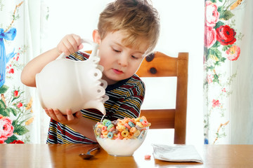 Boy pouring milk into a bowl of cereal