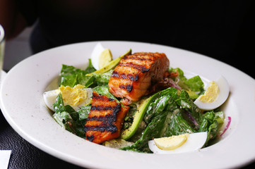 Grilled salmon over baby greens salad