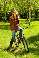 Fototapeta na wymiar Thinking woman on bicycle in the spring forest