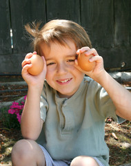 Young boy holding up two eggs