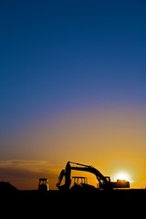 Construction equipment in silhouette, vertical