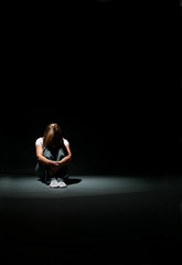 Woman sitting with her knees up and head down.