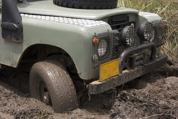 A gray jeep splattered and caked with mud