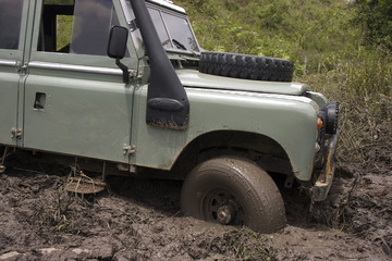 A gray jeep splattered and caked with mud