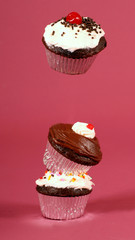 Three chocolate cupcakes stacked with one floating