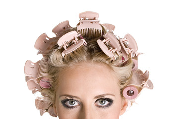 Young beautiful girl is having hair curlers on her head