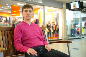 Fototapeta premium young man sits on bench in mall