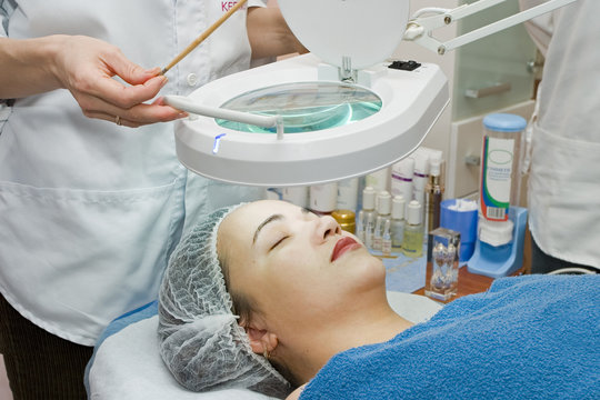 The cosmetician does face care procedure for the young woman