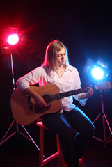 Obraz na płótnie Canvas Teenage girl with guitar and stage lights