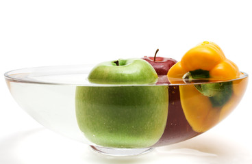 Green and red apples and yellow paprika in vase with water