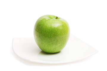 Green apple on white ceramic plate
