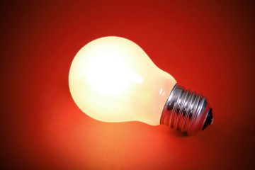 Glowing light bulb turned on over a orange background