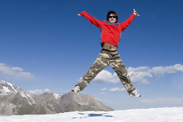 Teenager in red sport pullover jumping over blue sky, Tien Shan