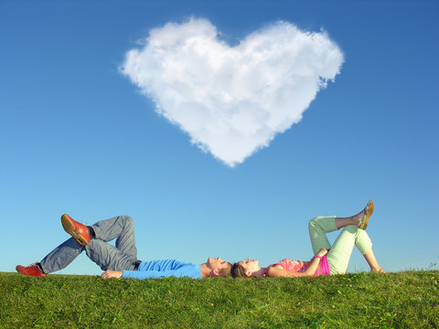 young pair lays on grass, In sky cloud in form of heart