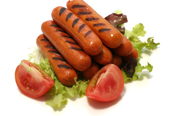 grilled sausages on green lettuce with tomatoe quarter