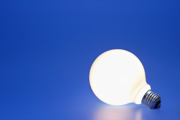 A lit up light bulb on a blue background.