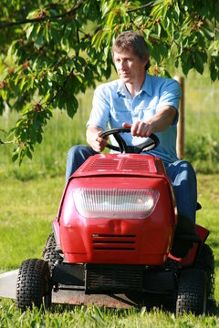 Mann beim Rasenmähen mit dem Aufsitzmäher im Garten