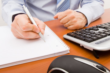 Business man writing in a notebook.