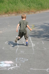 Kind beim Spielen auf der Straße mit kreide