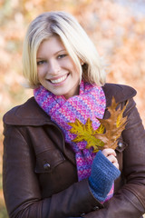 Young woman on walk holding leaf