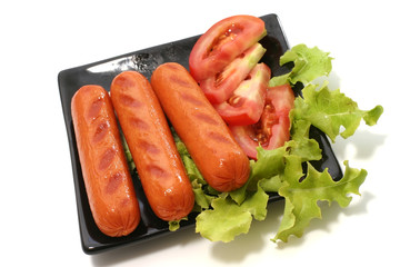 roast sausages on black dish with lettuce and tomato
