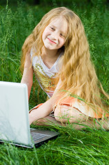 Funny little girl sitting with laptop outside