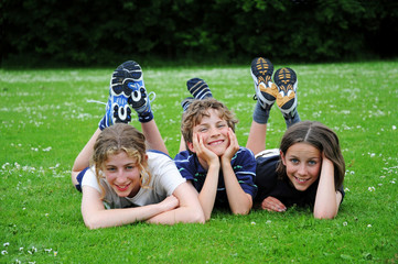three kids lying on the grass
