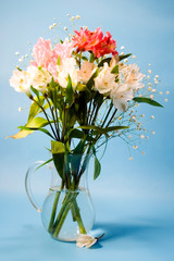 Flowers of alstroemeria in a transparent jug.
