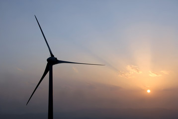 Wind power turbine in farm at sunset