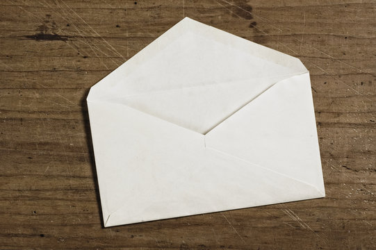 White envelope on wooden table, open, studio shot.