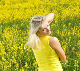 Naklejka na ściany i meble Beautiful young woman relaxing in a flower field