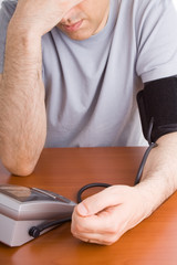 Man feeling sick checking his blood pressure.