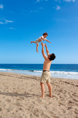 Father plays with his daughter on the summer beach