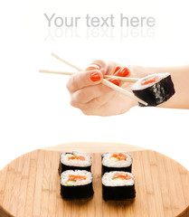 Hand holding sushi maki with wooden chopsticks