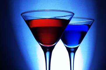 Red and blue cocktails on blue background, close up