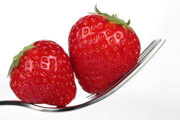 a couple of strawberries on a fork over white background
