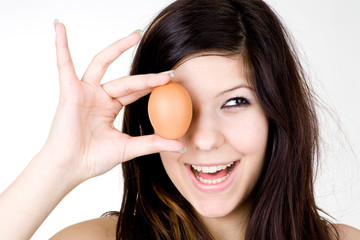 Lachende Frau hält Ei vors Gesicht