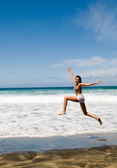 Fototapeta na wymiar happy woman jumping in the seaside under blue sky