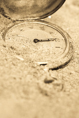 Vintage pocket clock buried in sand. Lost time concept.