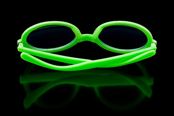 Bright green sunglasses on shiny black background