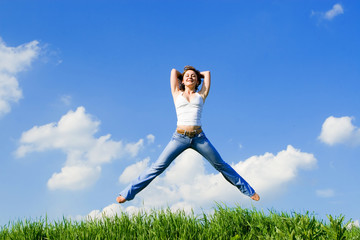 happy young woman jumping in green grass