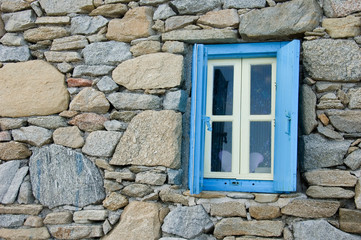 Fototapeta na wymiar Window in rock-surfaced wall of building - Greece