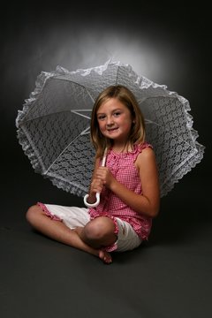 Pretty girl in red checkered shirt holding a lace parasol.