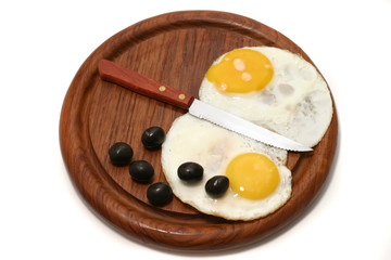 served fried egg on wooden plate with olives