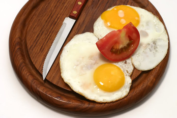 served fried egg on wooden plate with tomato