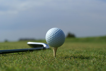 Golf ball in tall green grass set against blue sky