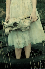 Girl holding animal skull. Old paper texture. Toned.