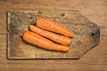 Three carrots on a cutting table.