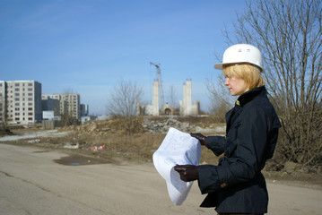 women architect with blueprints and hard hat at site
